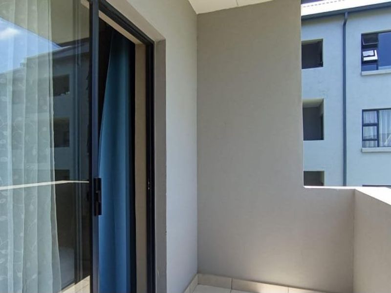 A private apartment balcony featuring tiled flooring and a sliding glass door entrance, offering a clean and functional outdoor space.