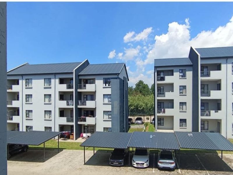 View of the apartment complex exterior featuring multi-story residential buildings and covered parking bays within the complex grounds.