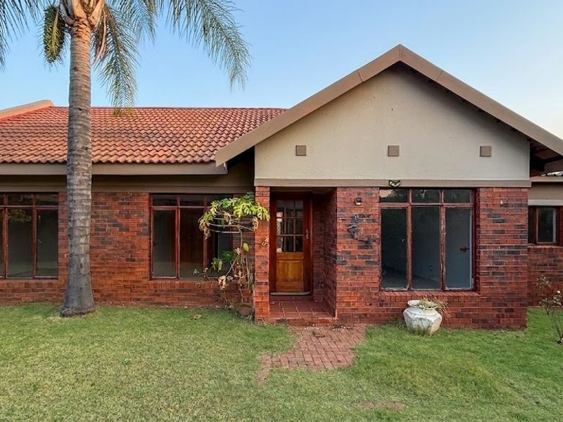 Front elevation of a face brick townhouse featuring a tiled roof, timber entrance door, and a front garden with a paved walkway.