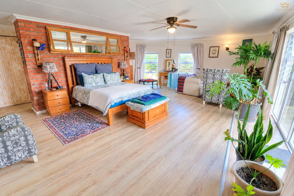 Spacious bedroom featuring an exposed brick wall, laminate flooring, ceiling fan, and large sliding glass doors providing ample natural light.