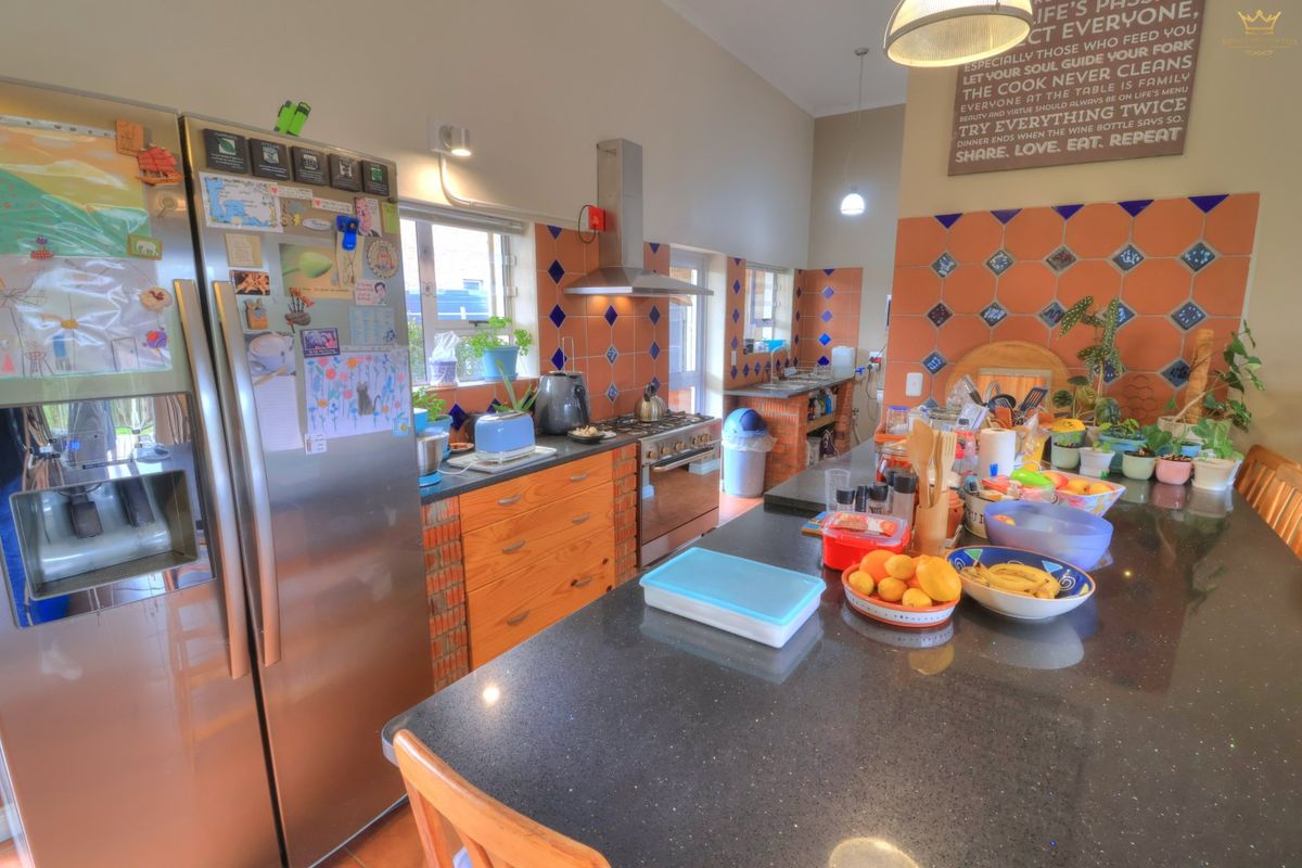 A spacious kitchen featuring a large granite island, wooden cabinetry, and a tiled backsplash, offering a functional layout with ample counter space.