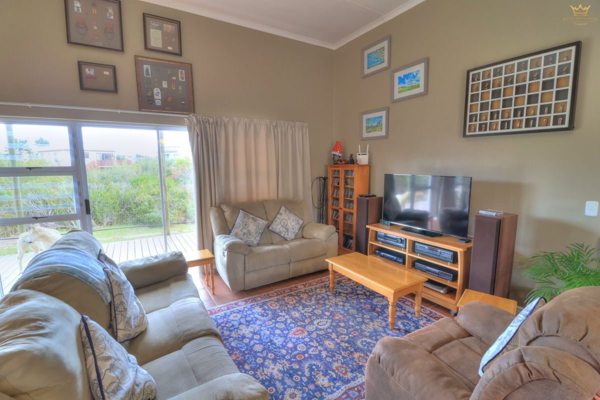 A comfortable living room featuring tiled flooring, cove cornicing, and a large sliding glass door providing access to the outdoor deck area.