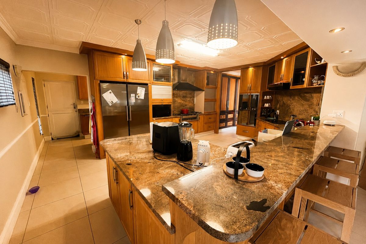 Spacious kitchen featuring extensive wooden cabinetry, granite countertops, a large central island with breakfast bar seating, and decorative coffered ceiling detail.