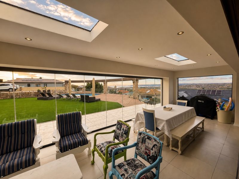 Spacious enclosed patio featuring large skylights, tiled flooring, and expansive frameless glass doors offering seamless indoor-outdoor flow and panoramic views.