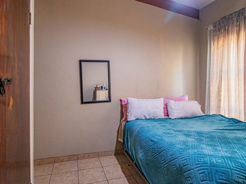 A functional bedroom featuring tiled flooring and neutral wall tones, providing a blank canvas for potential interior updates.
