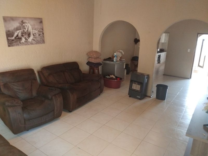 Open-plan living area featuring tiled flooring and arched architectural details, leading through to a kitchen space.
