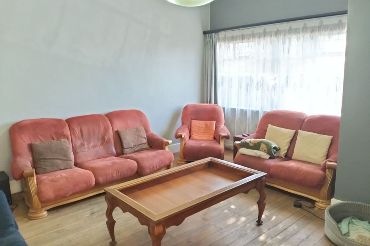 A comfortable living room featuring hardwood flooring and a large window with curtain fittings, providing a bright and functional space.