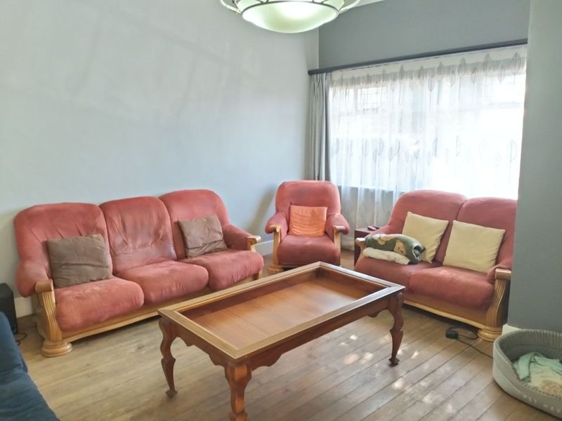 A comfortable living room featuring hardwood flooring and a large window with curtain fittings, providing a bright and functional space.