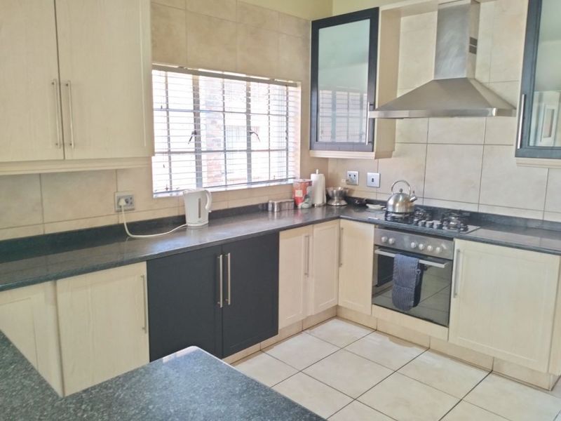 A functional kitchen featuring two-tone cabinetry, granite countertops, a built-in oven with gas hob, and a stainless steel extractor fan.