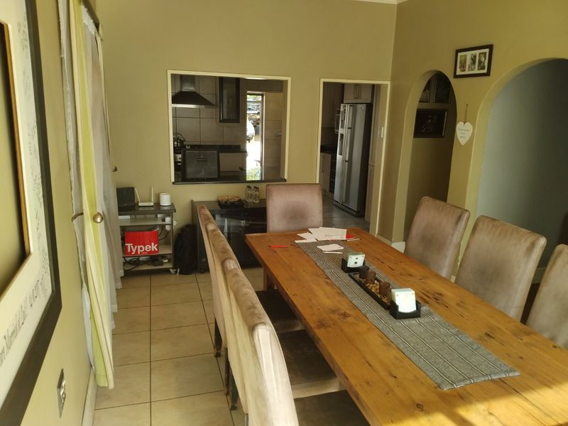 Dining room featuring tiled flooring and an arched entryway, with a convenient serving hatch connecting to the kitchen area.