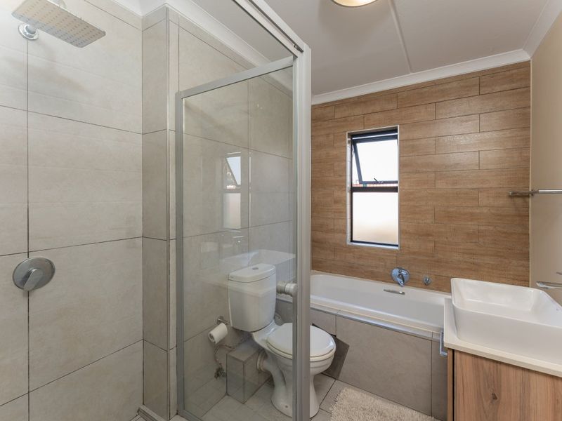 Modern bathroom featuring a walk-in shower with rainfall head, a built-in bathtub, a vessel sink vanity, and contemporary tiled finishes.