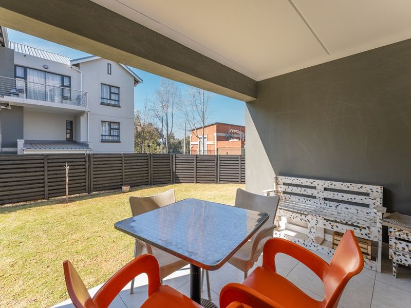 A covered patio area with tiled flooring, overlooking a private garden space with perimeter fencing.