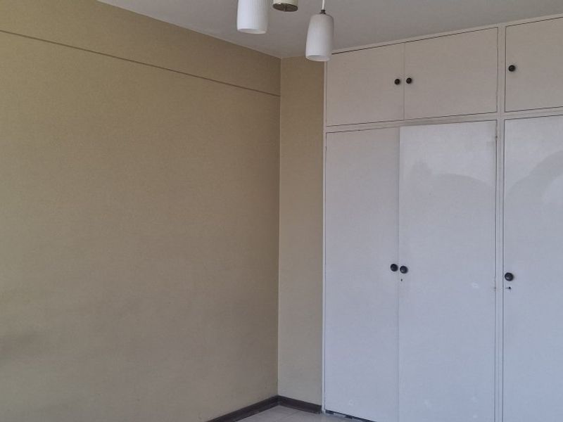 A vacant bedroom featuring built-in cupboards with integrated overhead storage and a simple pendant light fixture.