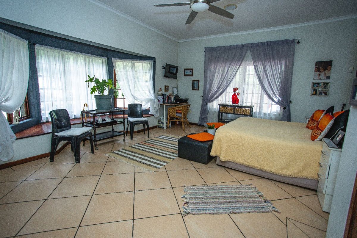Spacious bedroom featuring tiled flooring, a ceiling fan, and a large bay window that allows for ample natural light.