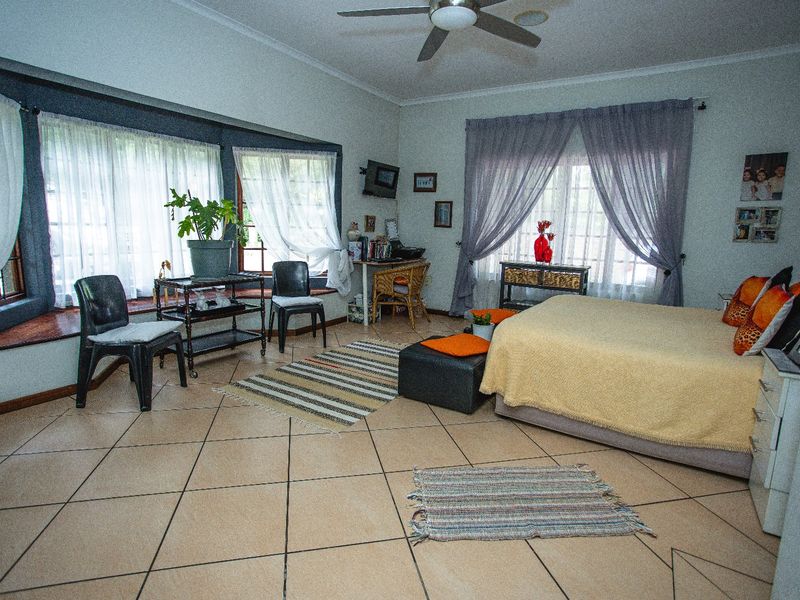 Spacious bedroom featuring tiled flooring, a ceiling fan, and a large bay window that allows for ample natural light.
