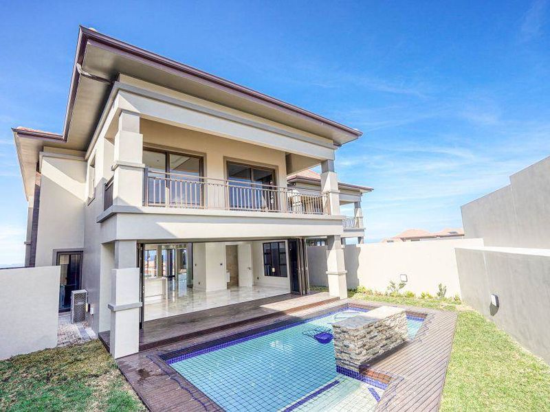 Rear view of a modern townhouse featuring a swimming pool, wooden decking, and a spacious covered balcony accessible via large sliding doors.