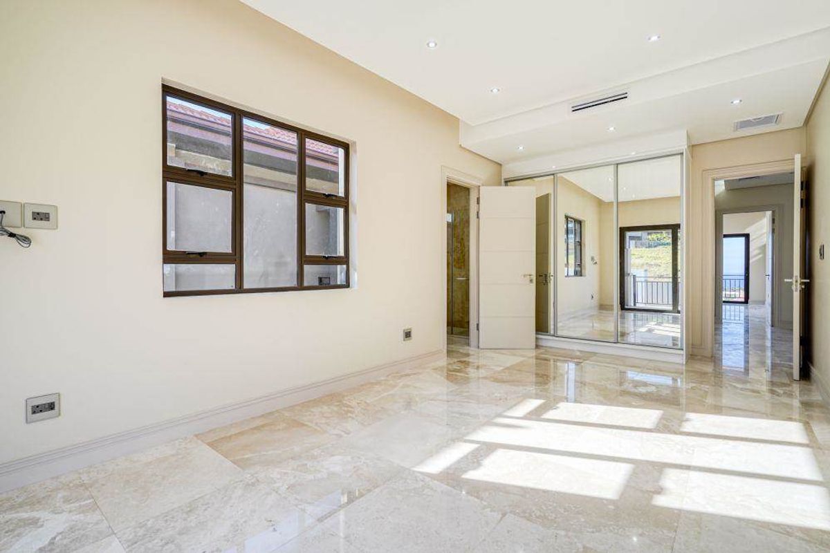 Spacious bedroom featuring polished marble flooring, mirrored built-in cupboards, recessed lighting, and ducted air conditioning, offering a bright and modern living space.
