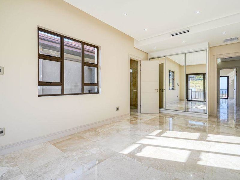 Spacious bedroom featuring polished marble flooring, mirrored built-in cupboards, recessed lighting, and ducted air conditioning, offering a bright and modern living space.