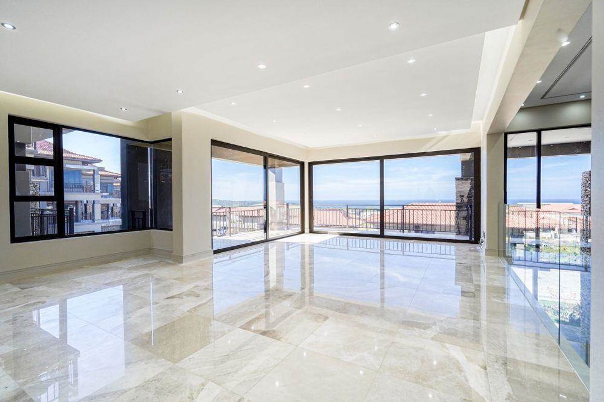 Spacious, light-filled living area featuring high-end marble flooring, recessed lighting, and expansive sliding glass doors offering panoramic views.