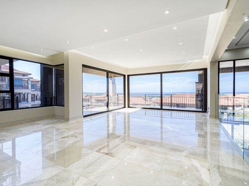 Spacious, light-filled living area featuring high-end marble flooring, recessed lighting, and expansive sliding glass doors offering panoramic views.