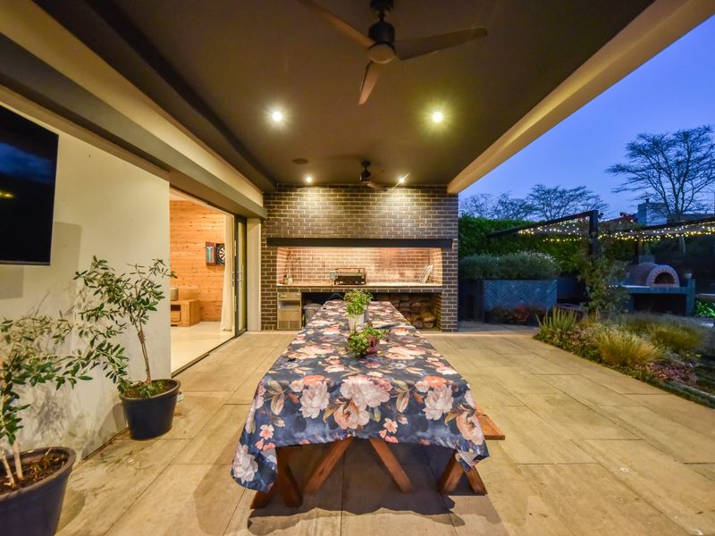 Spacious covered patio featuring a built-in braai, brick accent wall, recessed lighting, and seamless access to the interior living space.
