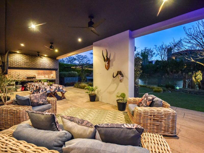 Spacious covered patio featuring a built-in braai, recessed lighting, ceiling fans, and direct access to the garden area.