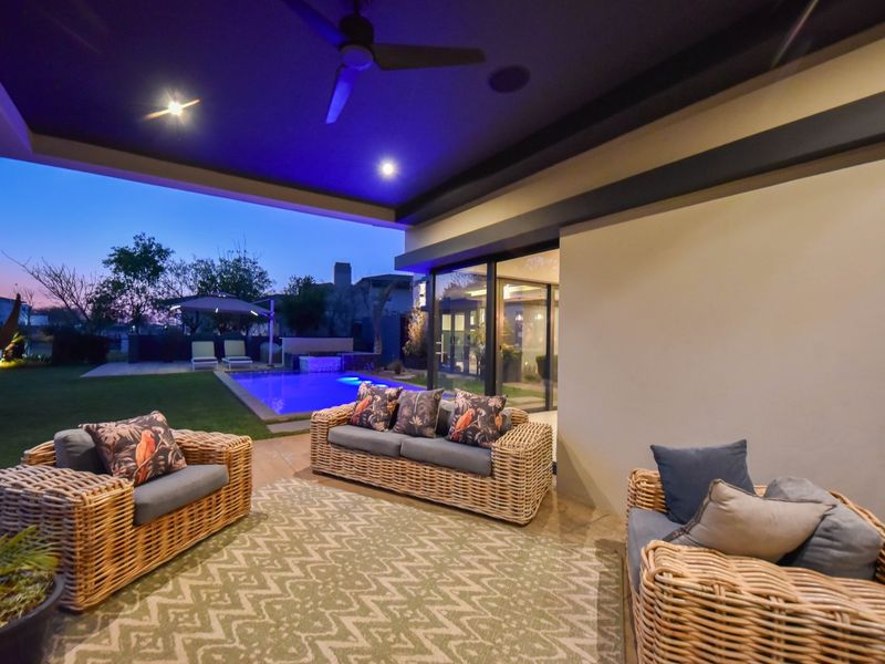 A covered outdoor patio area featuring recessed lighting, a ceiling fan, and direct access to the swimming pool and garden.