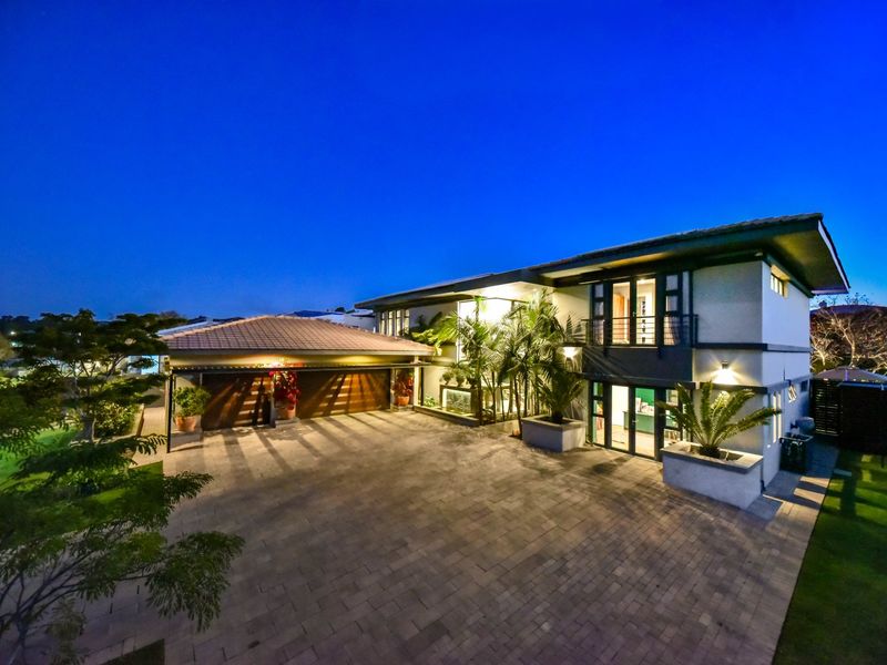 A well-maintained modern double-story residence featuring a spacious paved driveway, double garage, and integrated balcony, captured during twilight.