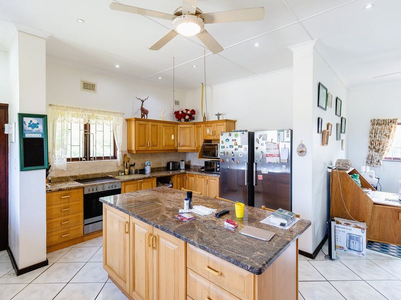 A functional kitchen featuring wooden cabinetry, granite countertops, a central island, and tiled flooring, offering a practical layout for cooking and meal preparation.