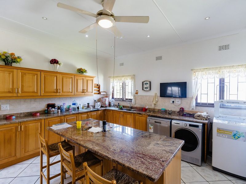 Spacious kitchen featuring wooden cabinetry, granite countertops, a central island, and tiled flooring, offering ample workspace and integrated appliance connections.