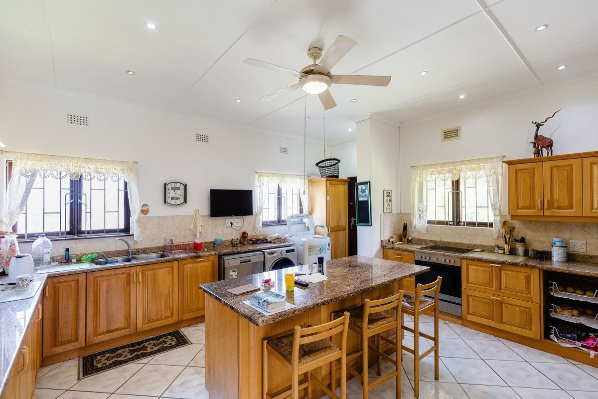 Spacious kitchen featuring wooden cabinetry, granite countertops, a central island, and tiled flooring, offering a functional layout with ample storage and workspace.