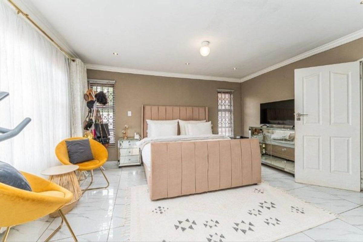 Spacious bedroom featuring polished tiled flooring, crown molding, and recessed lighting, offering a bright and well-maintained living space.