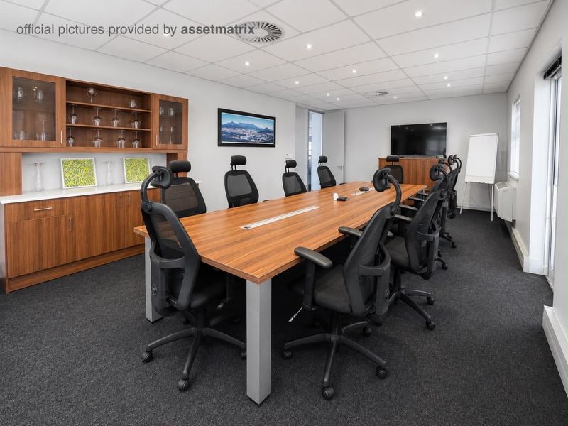 A professional boardroom or meeting room featuring built-in wooden cabinetry, recessed ceiling lighting, and a neutral interior finish.