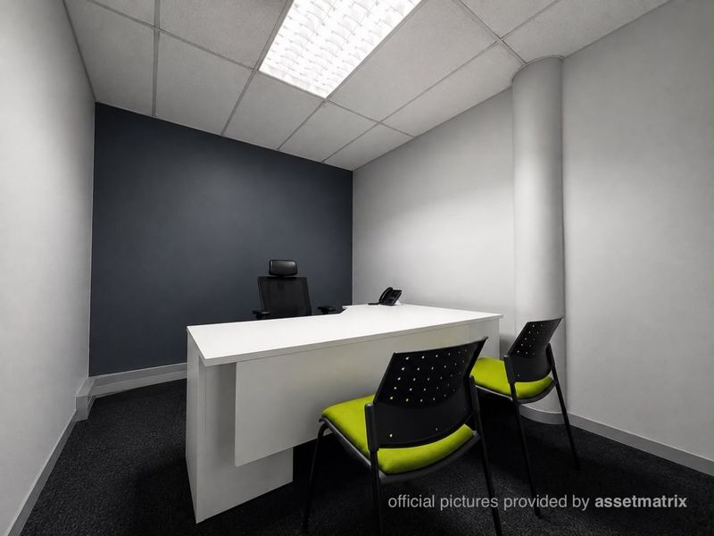 A professional office space featuring a suspended ceiling with recessed lighting, dark carpet flooring, and a prominent structural column.