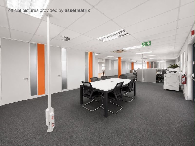 Open plan commercial office space featuring suspended ceilings, recessed lighting, carpeted flooring, and integrated power poles for flexible workstation connectivity.