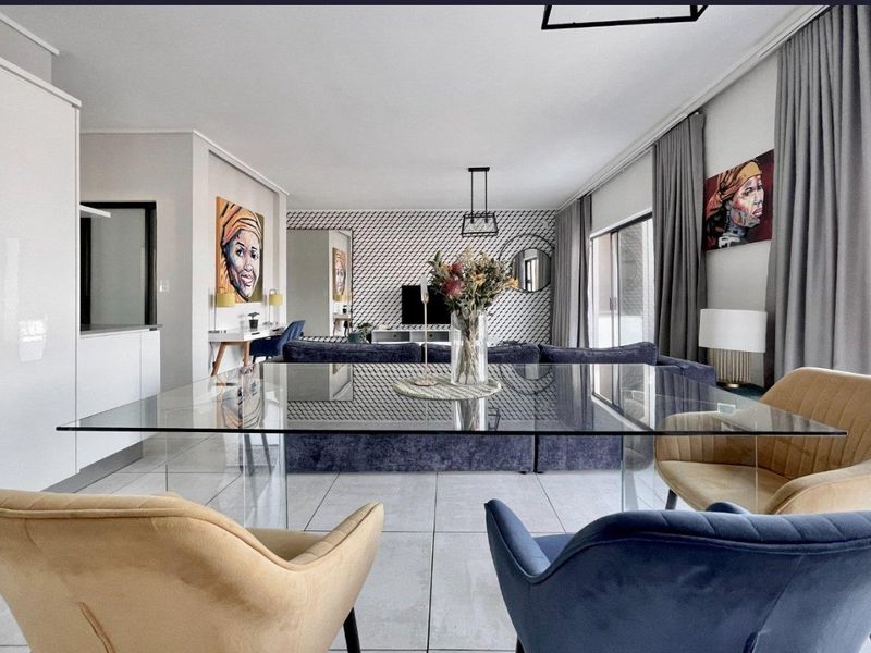 A modern open-plan living and dining area featuring large format floor tiles, neutral walls, and sliding glass doors leading to an outdoor space.