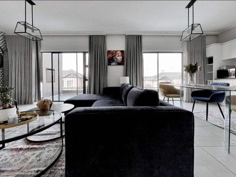 Modern open-plan living and dining area featuring tiled floors, contemporary pendant lighting, and large sliding glass doors leading to a balcony.