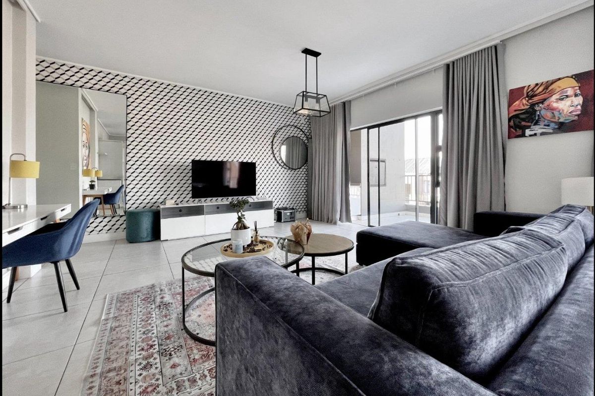 Modern living room featuring tiled floors, a striking patterned feature wall, and large sliding glass doors providing access to the balcony.