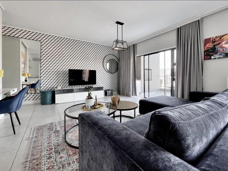 Modern living room featuring tiled floors, a striking patterned feature wall, and large sliding glass doors providing access to the balcony.