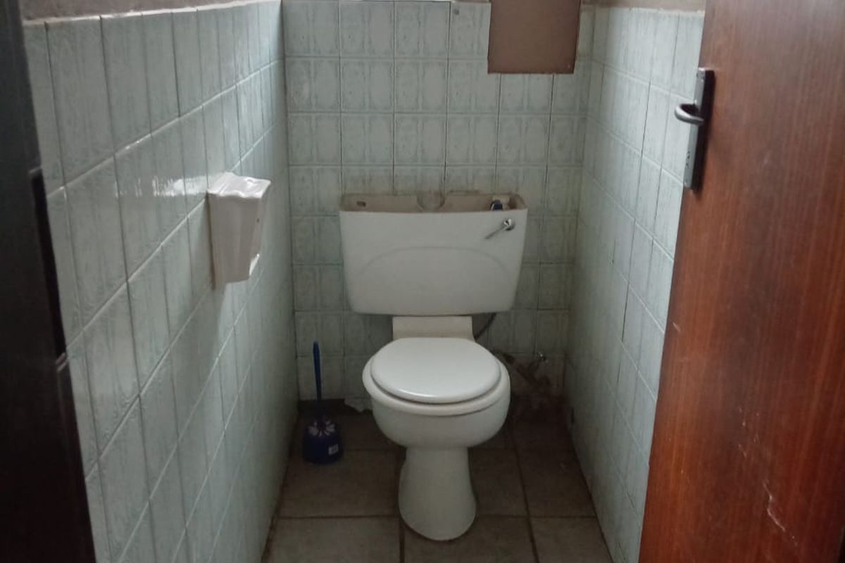 A small, dated bathroom featuring tiled walls and flooring, currently requiring maintenance and cosmetic updates to the fixtures and wall finishes.