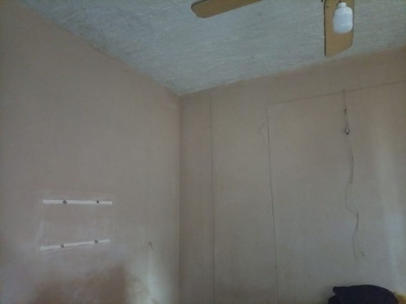 A vacant bedroom space featuring a ceiling fan, requiring cosmetic updates and wall repairs to improve the overall finish.