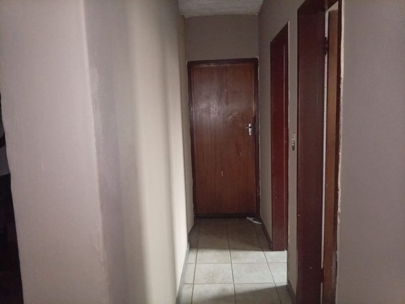 A simple interior hallway featuring tiled flooring and wooden door frames, providing access to various rooms within the apartment.