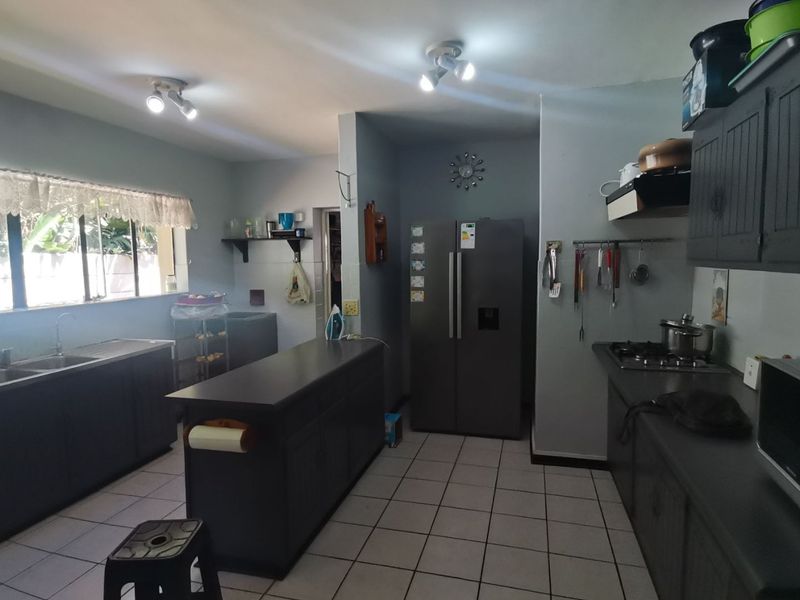 A functional kitchen featuring dark cabinetry, a central island, tiled flooring, and built-in cooking appliances, offering a practical layout for meal preparation.