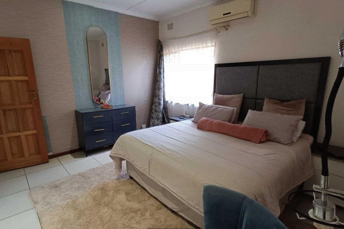 A bedroom featuring tiled flooring, an installed air conditioning unit, and a wooden door.