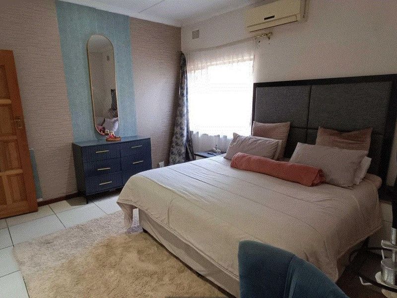 A bedroom featuring tiled flooring, an installed air conditioning unit, and a wooden door.