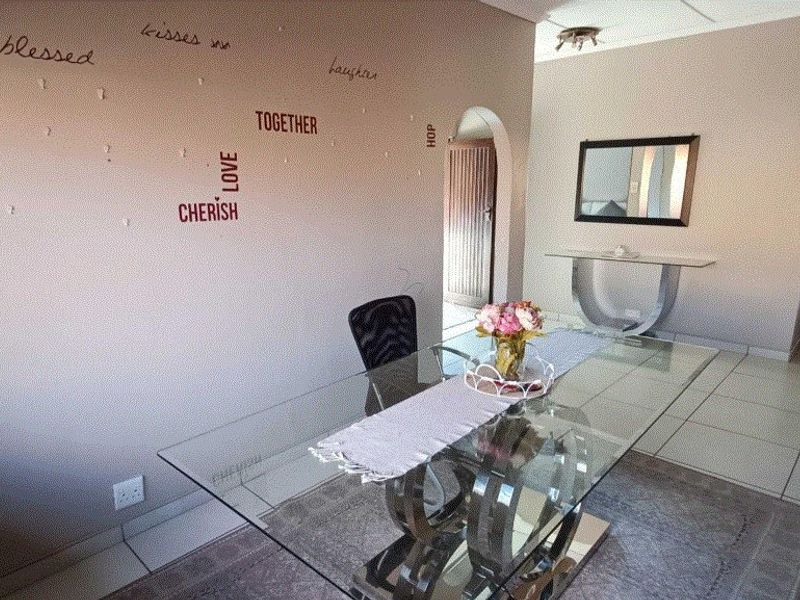 A dining area featuring tiled flooring and an arched doorway, providing a functional space for meals with neutral wall finishes.