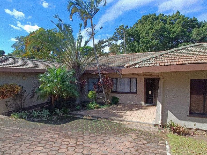 Front elevation of a single-story house featuring a tiled roof, paved driveway, and an integrated garage with established garden landscaping.
