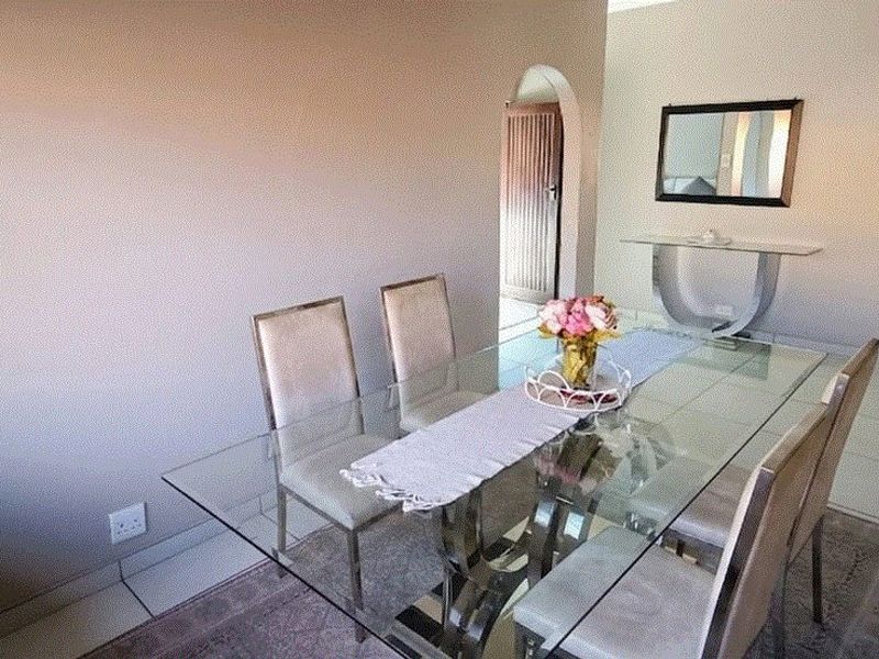A bright dining room featuring tiled flooring and a classic architectural archway leading to an adjacent space.