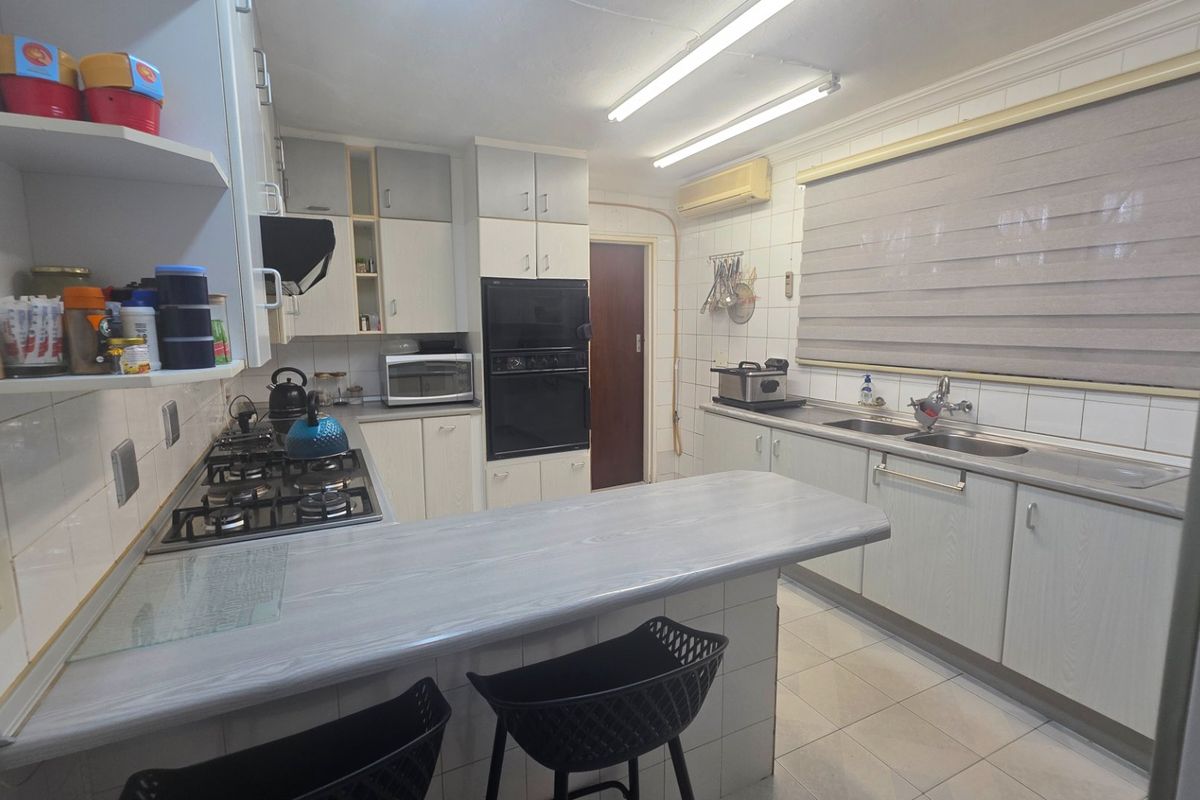 Functional kitchen featuring a gas hob, built-in oven, double sink, and ample cabinetry with a breakfast bar counter.