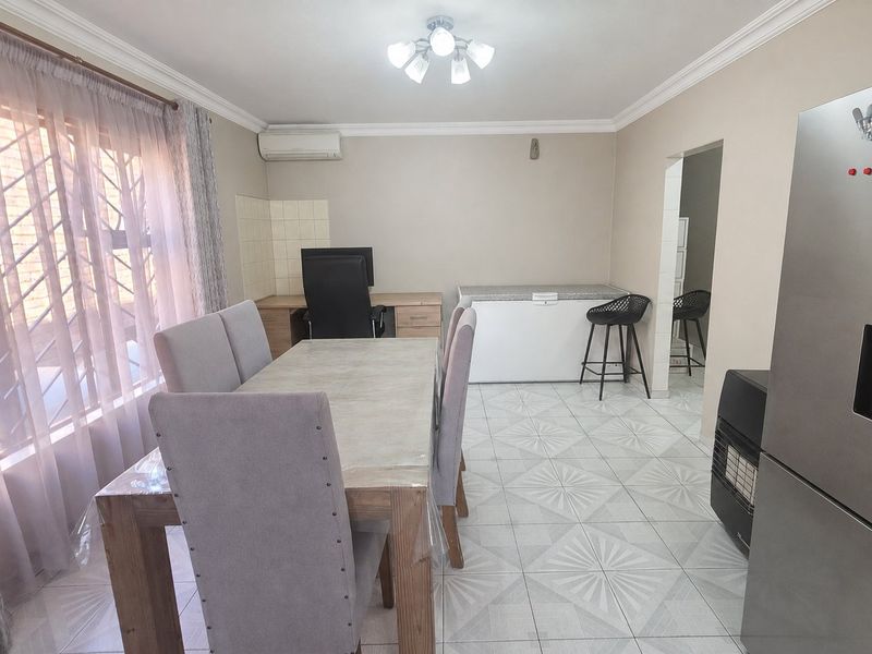 Open plan dining and living area featuring tiled flooring, split-system air conditioning, and security bars on the windows.